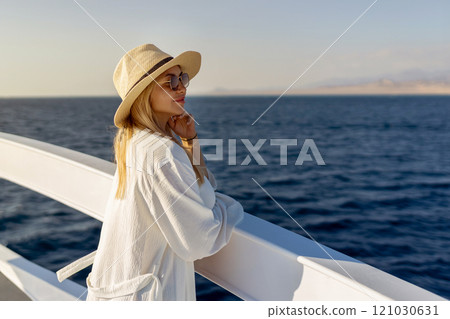 Elegant sexy woman in white dress standing near railings and looking on sunset. Like yacht style. 121030631