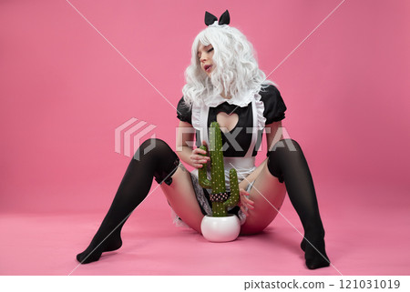 A sexy girl in an erotic maid costume from a sex shop on a pink background of a copy paste sits on the floor 121031019