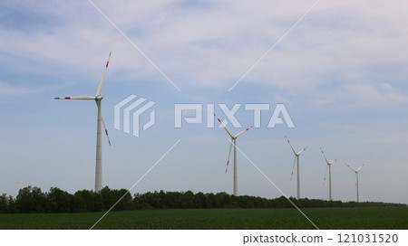 row of wind turbines in green field with underbrush against cloudy sky, industrial technological landscape in natural area, windmills in industrial use row of wind turbines in green field with underbrush against cloudy sky, industrial technological landscape in natural area, windmills in industrial use 121031520