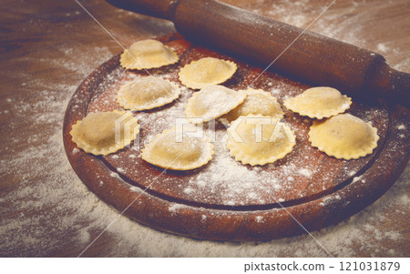 fresh raw, uncooked ravioli, on a cutting board, with a rolling pin for dough, wooden background, no people, fresh raw, uncooked ravioli, on a cutting board, with a rolling pin for dough, wooden background, no people, 121031879