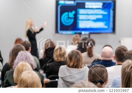 Audience attentively listens to speaker during a business presentation in conference room 121031987
