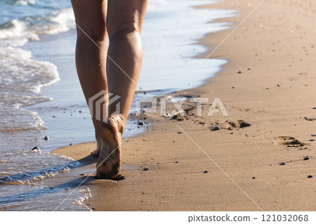 Woman walk along the sea beach on a sunny day on vacation. The concept of rest, vacation packages, relaxation Woman walk along the sea beach on a sunny day on vacation. The concept of rest, vacation packages, relaxation 121032068