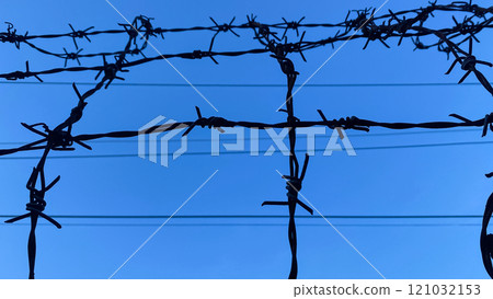 barbed wire against the sky on a high fence 121032153