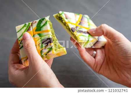Trend Dubai white chocolate with pistachio paste and kataifi dough in woman hands. Confectionery handmade sweets at home in the kitchen.  121032741