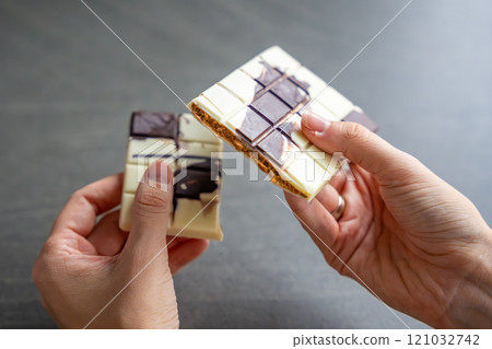 Piece of trend Dubai white chocolate with halva paste in woman hands. Confectionery handmade sweets at home in the kitchen.  121032742