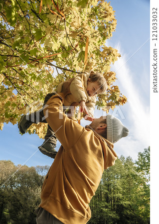 Father with a small child in nature under a tree. Family love and care for children 121033032