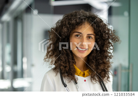 A smiling woman doctor with curly hair and a stethoscope, standing confidently in a contemporary medical facility. She radiates professionalism and warmth. A smiling woman doctor with curly hair and a stethoscope, standing confidently in a contemporary medical facility. She radiates professionalism and warmth. 121033584