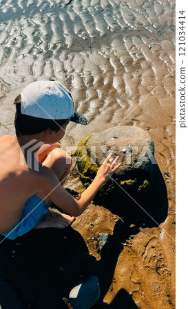 boy plays with stones on ribbed sand on the shore of the White Sea boy plays with stones on ribbed sand on the shore of the White Sea 121034414