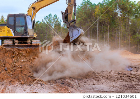 An excavator is used to move earth into dump truck at construction site An excavator is used to move earth into dump truck at construction site 121034601