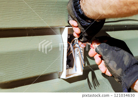Wires are carefully installed into wall cavity by gloved hand. 121034630