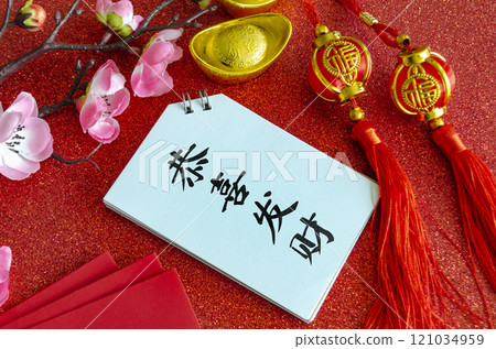 Top view of Chinese New Year saying Gong Xi Fa Cai on white notepad with Chinese New Year decoration background 121034959