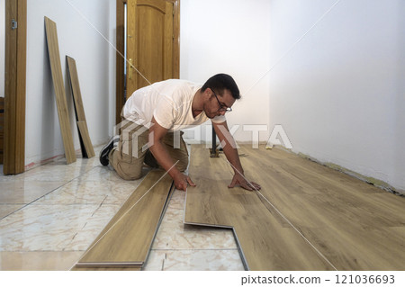 Adult man installing a parquet laminate floor in a business 121036693