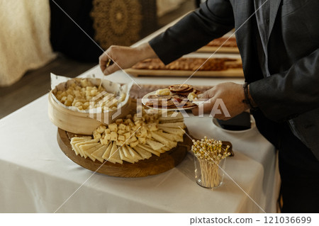 close up view of a man taking cheese from a caterer during an event 121036699