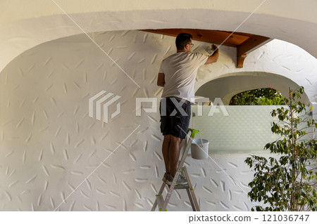 Caucasian man painting a house, perfect for home renovation and DIY projects 121036747