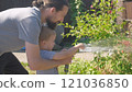 Father and Son. Funny little boy watering lawn plants in garden housing backyard with Dad. Summer house work. Hardworking preschool Kid outdoors. Children help with housework. activity for kids 121036850