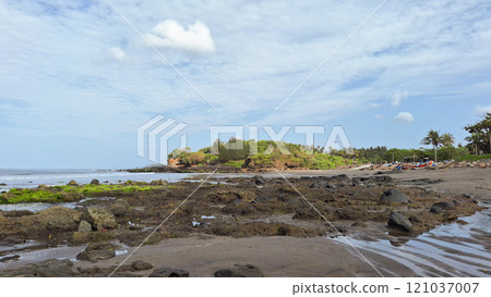 Beautiful balinese landscape. Ocean beach. Ancient hinduism temple Tanah lot on the rock against cloudy sky. Bali Island, Indonesia 121037007
