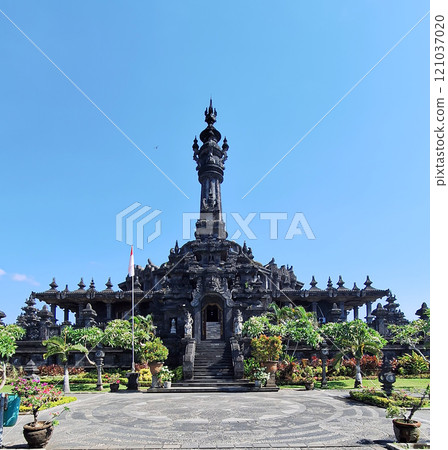 Visitors walking along the pathway toward the Bajra Sandhi Monument in Denpasar, Bali, surrounded by vibrant green trees and sunny weather Visitors walking along the pathway toward the Bajra Sandhi Monument in Denpasar, Bali, surrounded by vibrant green trees and sunny weather 121037020