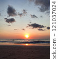 A serene beach with a glowing sunset reflecting on gentle waves and a quiet sandy shoreline. 121037024