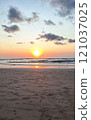 A serene beach with a glowing sunset reflecting on gentle waves and a quiet sandy shoreline. 121037025