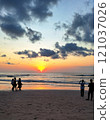 Golden sunset reflecting on calm waves and sandy beach with scattered clouds in the sky. 121037026