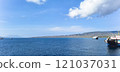 A serene view of the Bali Sea with calm blue waters, distant mountains, and scattered boats under a clear sky. 121037031