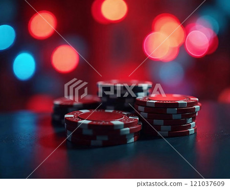 Red poker chips are arranged in neat stacks against a backdrop of colorful bokeh lights, creating an inviting yet mysterious vibe. 121037609