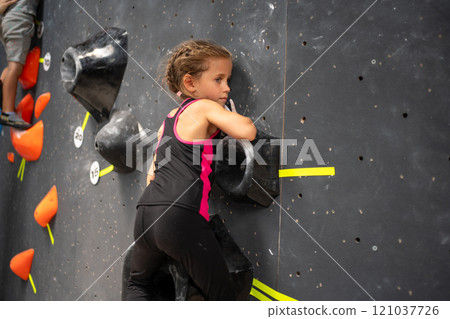 Determined girl climbing artificial rock wall at 121037726