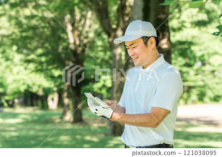 Male golfer using smartphone on golf course (app, score, score management, course strategy, course map) 121038095
