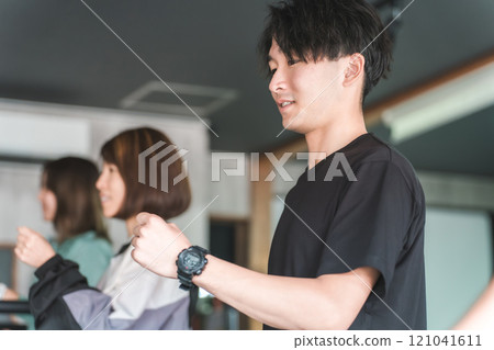 亞洲男性和女性在健身房使用室內跑步機和跑步機進行步行和有氧運動 121041611