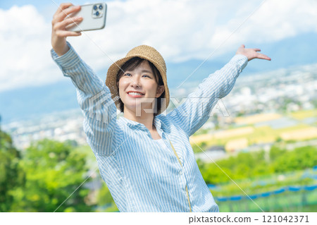 A woman taking pictures of beautiful scenery with her smartphone. A woman traveling. 121042371