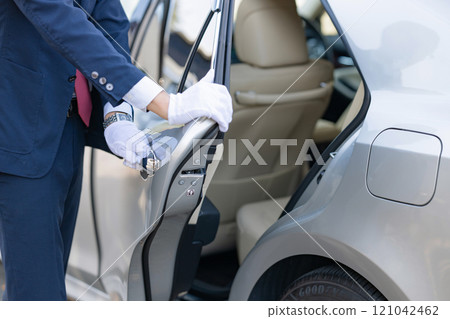 Driver opening the back door of a car 121042462