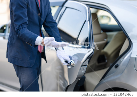 Driver opening the back door of a car 121042463