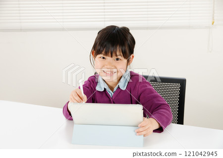 An elementary school girl happily studying while operating a tablet An elementary school girl happily studying while operating a tablet 121042945