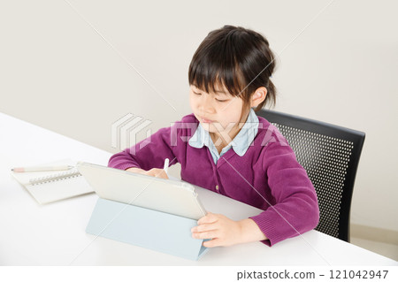 An elementary school girl concentrating while studying on a tablet An elementary school girl concentrating while studying on a tablet 121042947