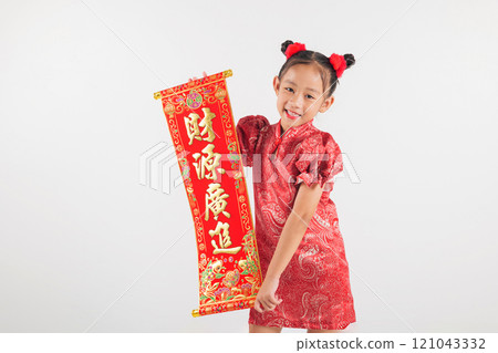 Happy Chinese New Year Smiling little Asian girl in red qipao dress holding spring festival couplets with "FU," representing blessings and fortune. Isolated on white background 121043332