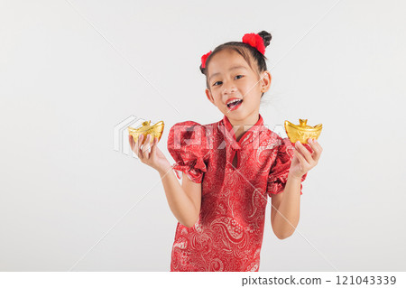 Happy Chinese New Year Smiling Asian girl wearing a red cheongsam dress holds a gold ingot, symbolizing wealth and prosperity. Isolated on a white background, festive and traditional Happy Chinese New Year Smiling Asian girl wearing a red cheongsam dress holds a gold ingot, symbolizing wealth and prosperity. Isolated on a white background, festive and traditional 121043339