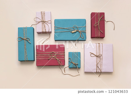 Various colorful gift boxes tied with rustic twine arranged on beige surface 121043633