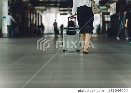 The feet of a business woman on a business trip or return from a trip with a suitcase at the station 121044064