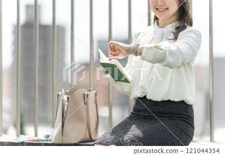 A young Asian business woman checking her schedule, plans, and time while looking at her watch. 121044354