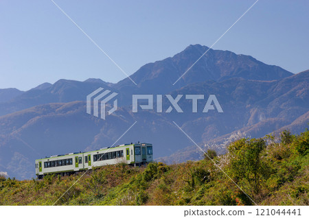 The Koumi Line Kiha 110 series train travels through Omagari with the blue hazy Mount Kaikoma in the background. The Koumi Line Kiha 110 series train travels through Omagari with the blue hazy Mount Kaikoma in the background. 121044441