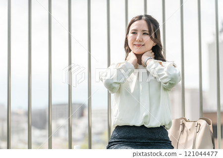 A young Asian business woman applying sunscreen and antiperspirant on her neck (UV protection, deodorant, skin care) 121044477