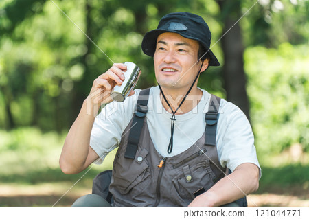 一名男子在露營地享受露營和豪華露營(飲用水、咖啡和啤酒) 一名男子在露營地享受露營和豪華露營(飲用水、咖啡和啤酒) 121044771