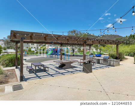 Covered gathering area in city park with green wood picnic tables 121044853