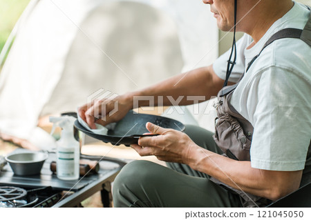 Male camper cleaning up after solo camping 121045050