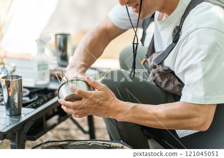 Male camper cleaning up after solo camping 121045051