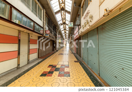 A deserted shopping street with its shutters down 121045384