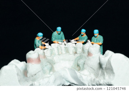 Miniature surgeons working on a dental model, showcasing the intricacies of dental procedures in a unique and artistic manner Miniature surgeons working on a dental model, showcasing the intricacies of dental procedures in a unique and artistic manner 121045746