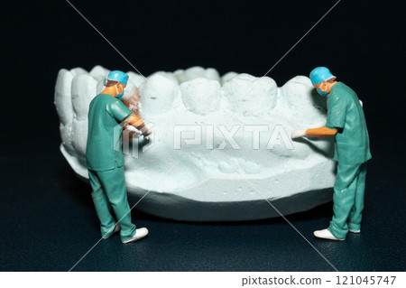 Miniature surgeons working on a dental model, showcasing the intricacies of dental procedures in a unique and artistic manner Miniature surgeons working on a dental model, showcasing the intricacies of dental procedures in a unique and artistic manner 121045747