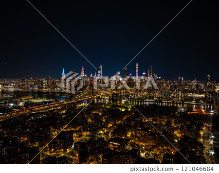 Illuminated Queensboro Bridge connecting Manhattan and Queens, part of the stunning New York City skyline glowing at night 121046684