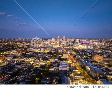 Aerial view of New Orleans skyline illuminating at dusk, showcasing vibrant city lights, prominent buildings, and the iconic Caesar Superdome under a beautiful twilight sky Aerial view of New Orleans skyline illuminating at dusk, showcasing vibrant city lights, prominent buildings, and the iconic Caesar Superdome under a beautiful twilight sky 121046687